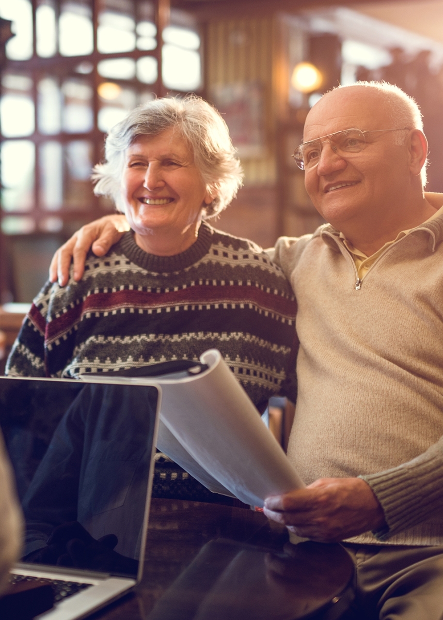 Senior man and woman sitting embraced during a business meeting with their financial advisor and talking to him.